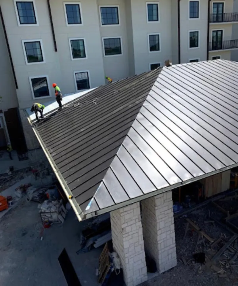 Crew installing standing seam metal roof panels on a commercial project in Colts Neck